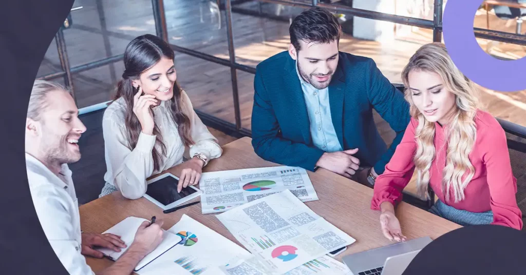 Grupo de profissionais discutindo gráficos em uma mesa sobre canais para Go to Market.